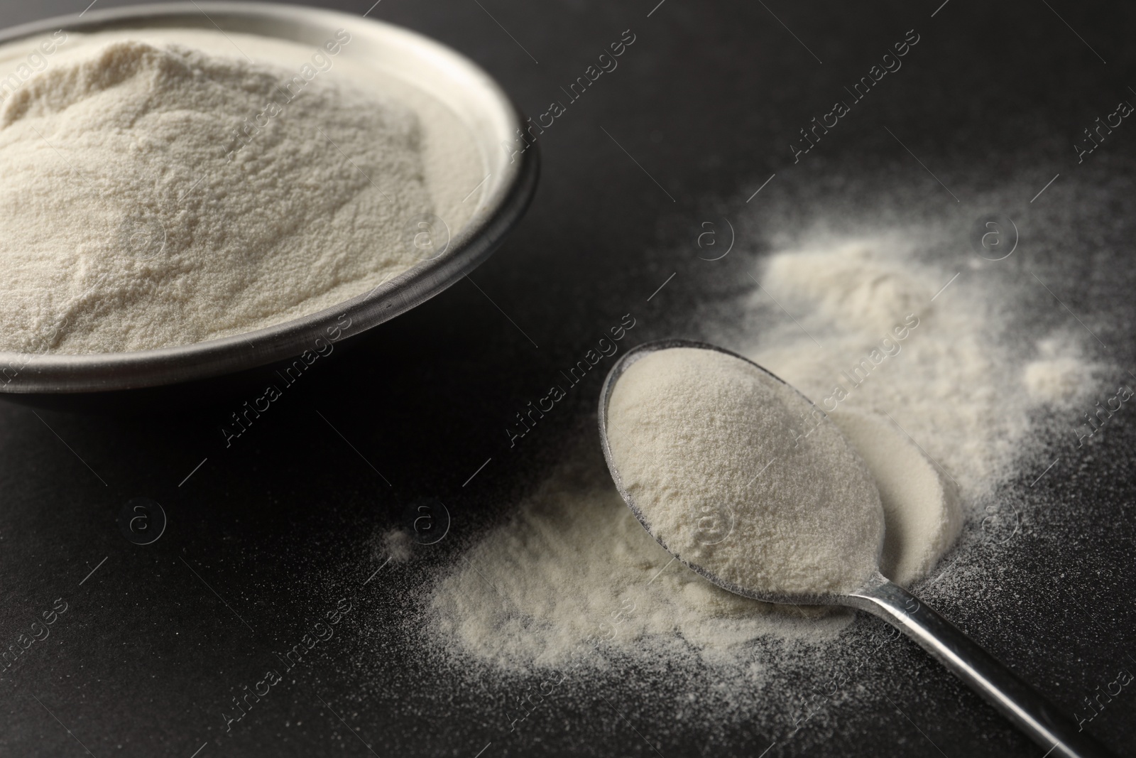 Photo of Bowl and spoon of agar-agar powder on black background, closeup