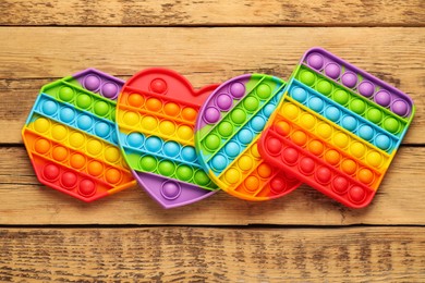 Photo of Rainbow pop it fidget toys on wooden table, flat lay