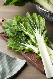 Photo of Leaves of fresh green pak choy cabbage with water drops on wooden table