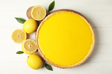 Delicious homemade lemon pie and fresh fruits on white wooden table, flat lay