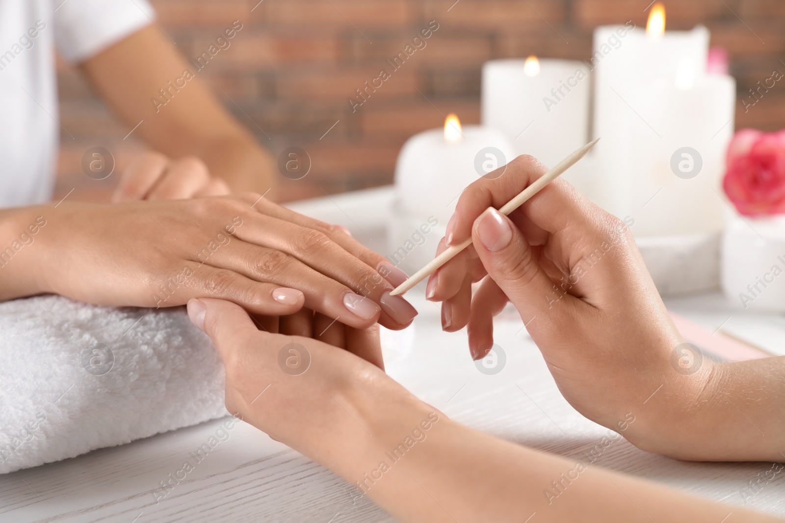 Photo of Manicurist working with client's nails at table, closeup. Spa treatment