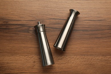 Photo of Stainless salt and pepper shakers on wooden table, flat lay