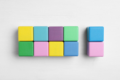 Photo of Flat lay composition with colorful cubes on white wooden background. Pareto principle concept