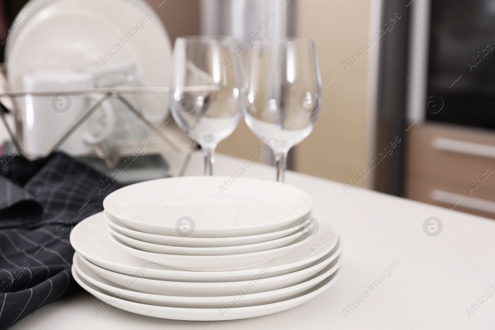 Photo of Stack of clean dishes and glasses on table in kitchen