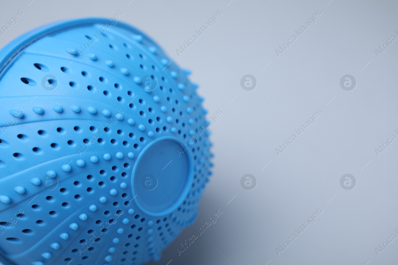 Photo of Laundry dryer ball on light grey background, closeup. Space for text