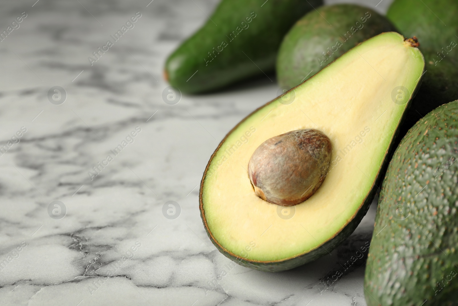 Photo of Delicious ripe avocados on white marble table