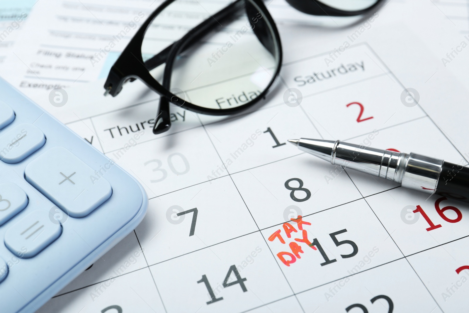 Photo of Tax day. Calendar with date reminder, pen, glasses and calculator on table, closeup