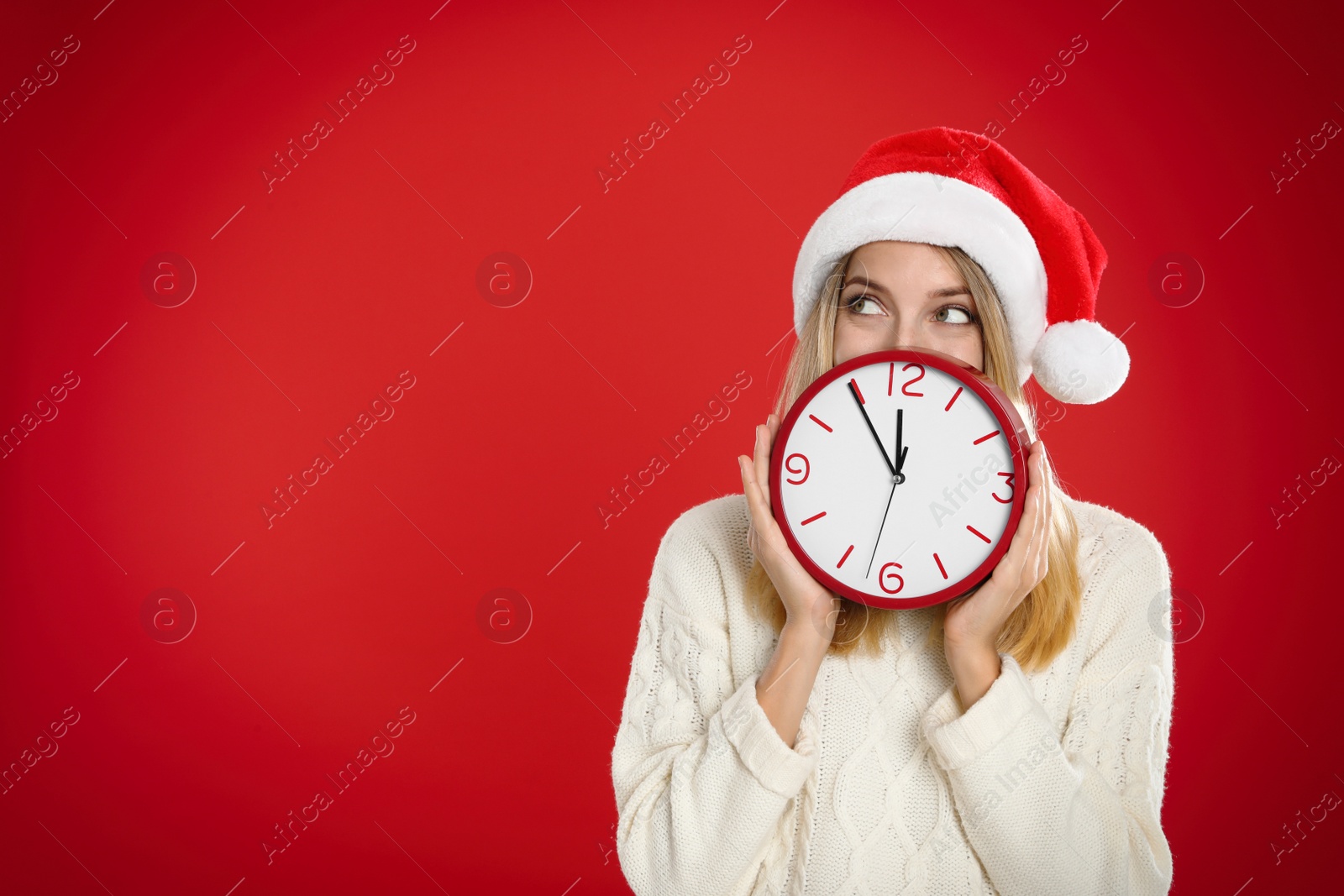Photo of Woman in Santa hat with clock on red background, space for text. New Year countdown