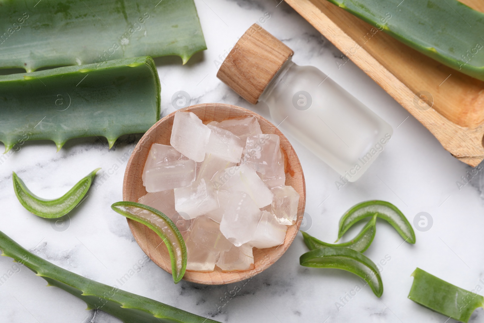 Photo of Aloe vera gel, bottle and slices of plant on white marble table, flat lay