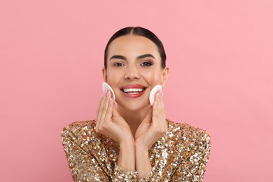 Photo of Beautiful woman removing makeup with cotton pads on pink background