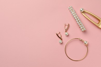 Photo of Elegant hair clips, bracelet and earrings with pearls on pink background, flat lay. Space for text