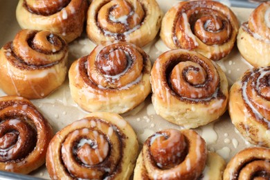 Tasty cinnamon rolls with cream on parchment paper, closeup