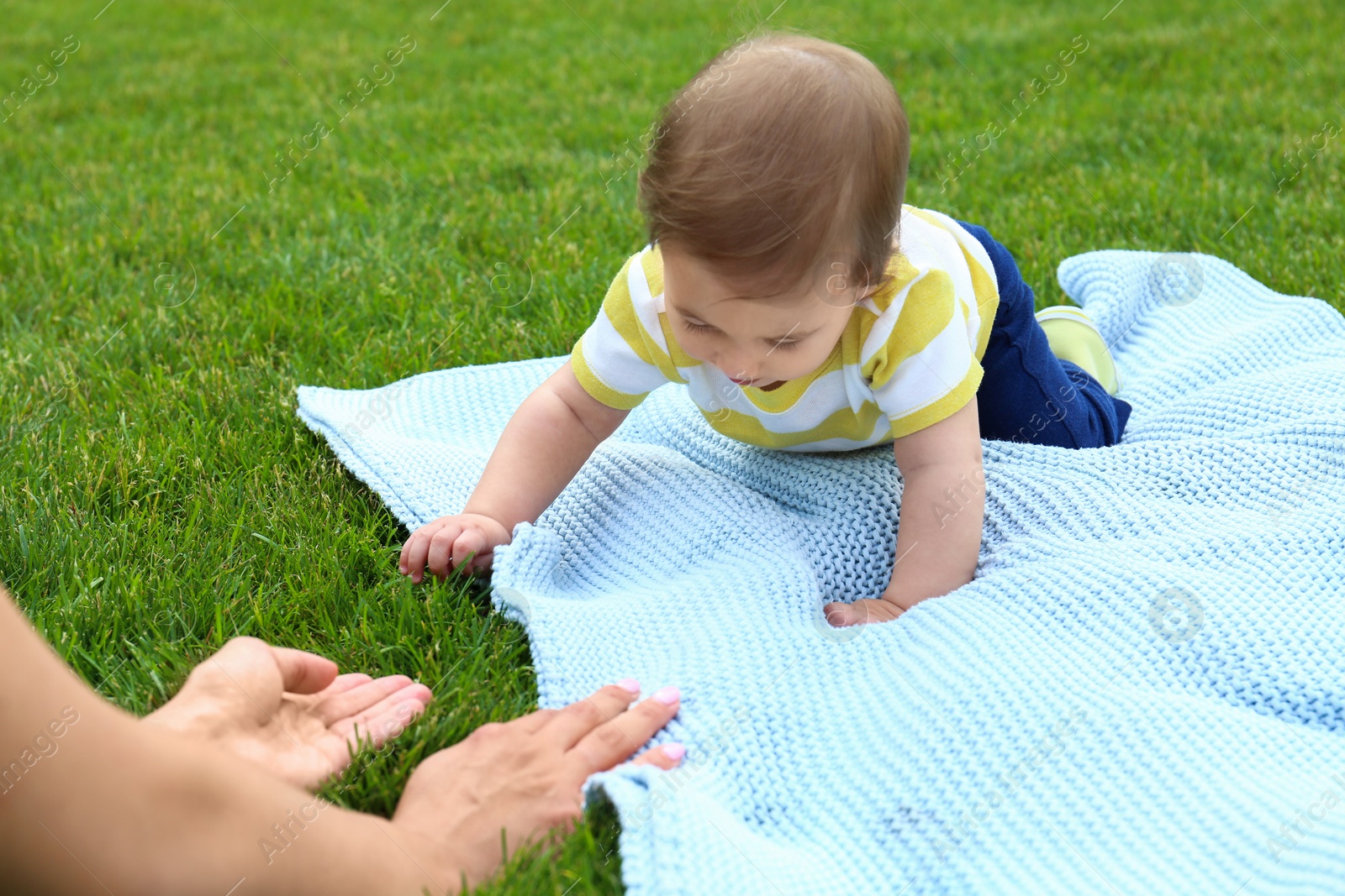 Photo of Adorable little baby crawling towards mother on blanket outdoors