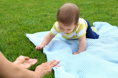 Adorable little baby crawling towards mother on blanket outdoors