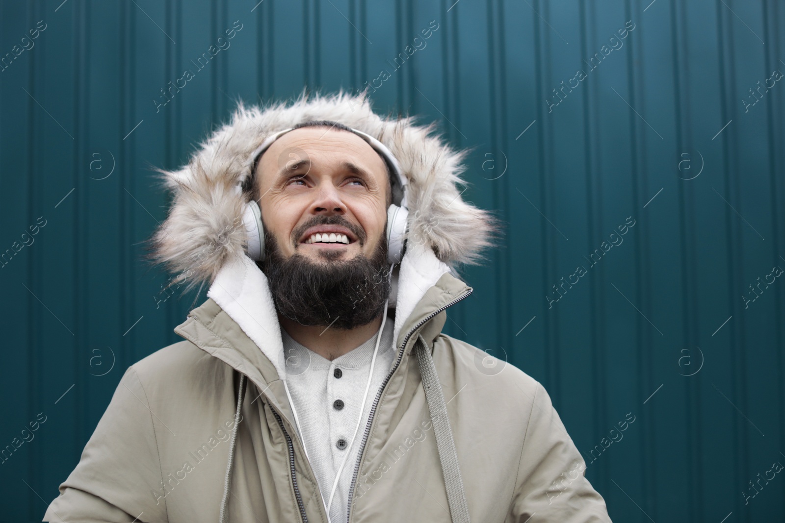 Photo of Mature man with headphones listening to music near color wall. Space for text