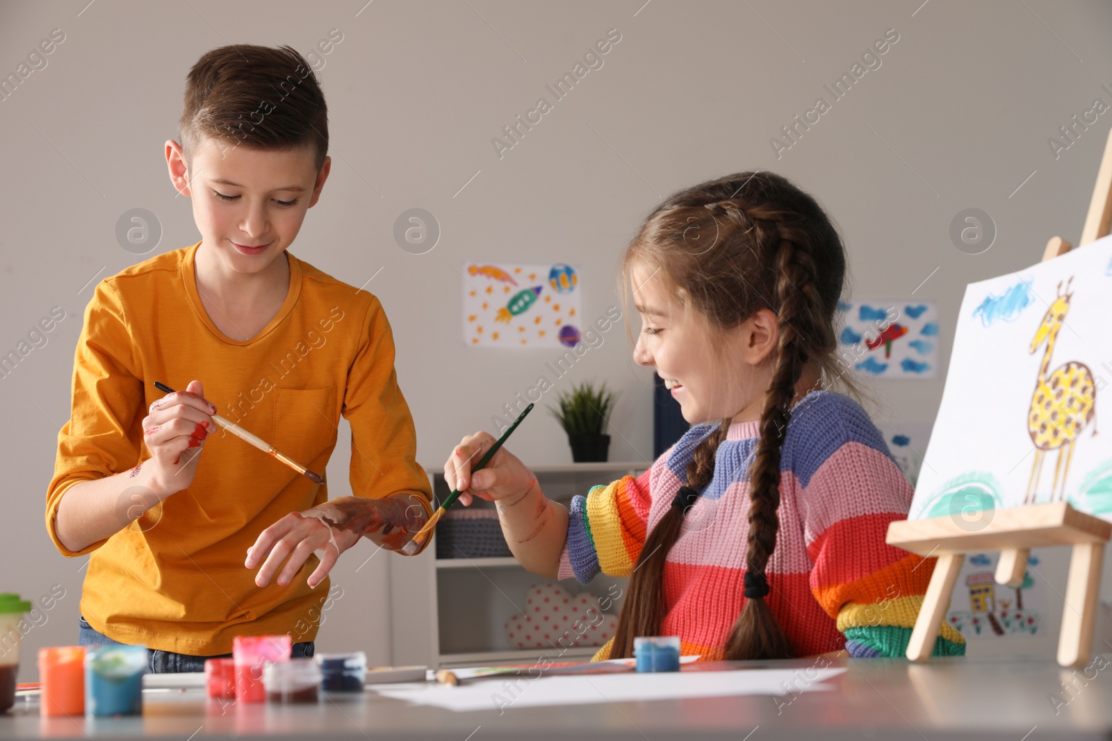 Photo of Little children having fun with paints at table indoors