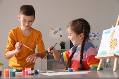 Little children having fun with paints at table indoors