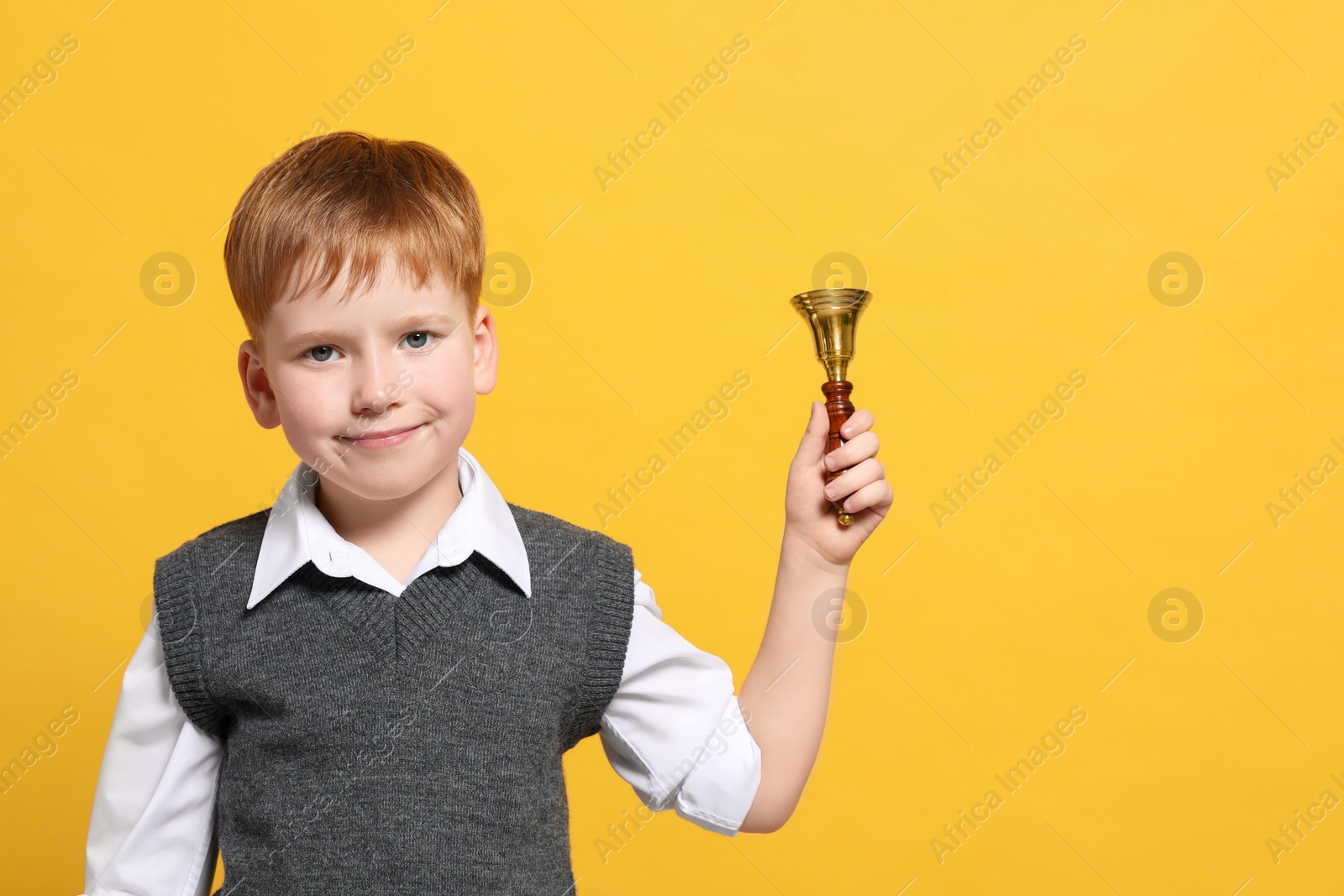 Photo of Pupil with school bell on orange background. Space for text