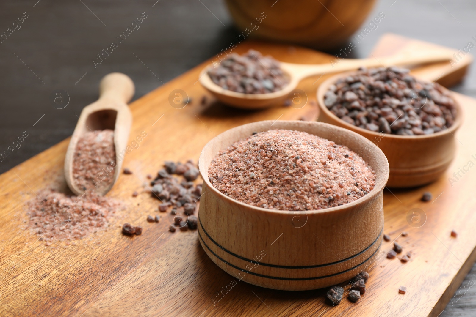 Photo of Black salt on wooden board, closeup view