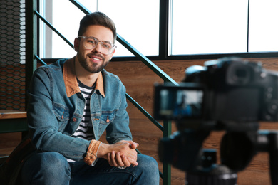 Young blogger recording video on camera indoors