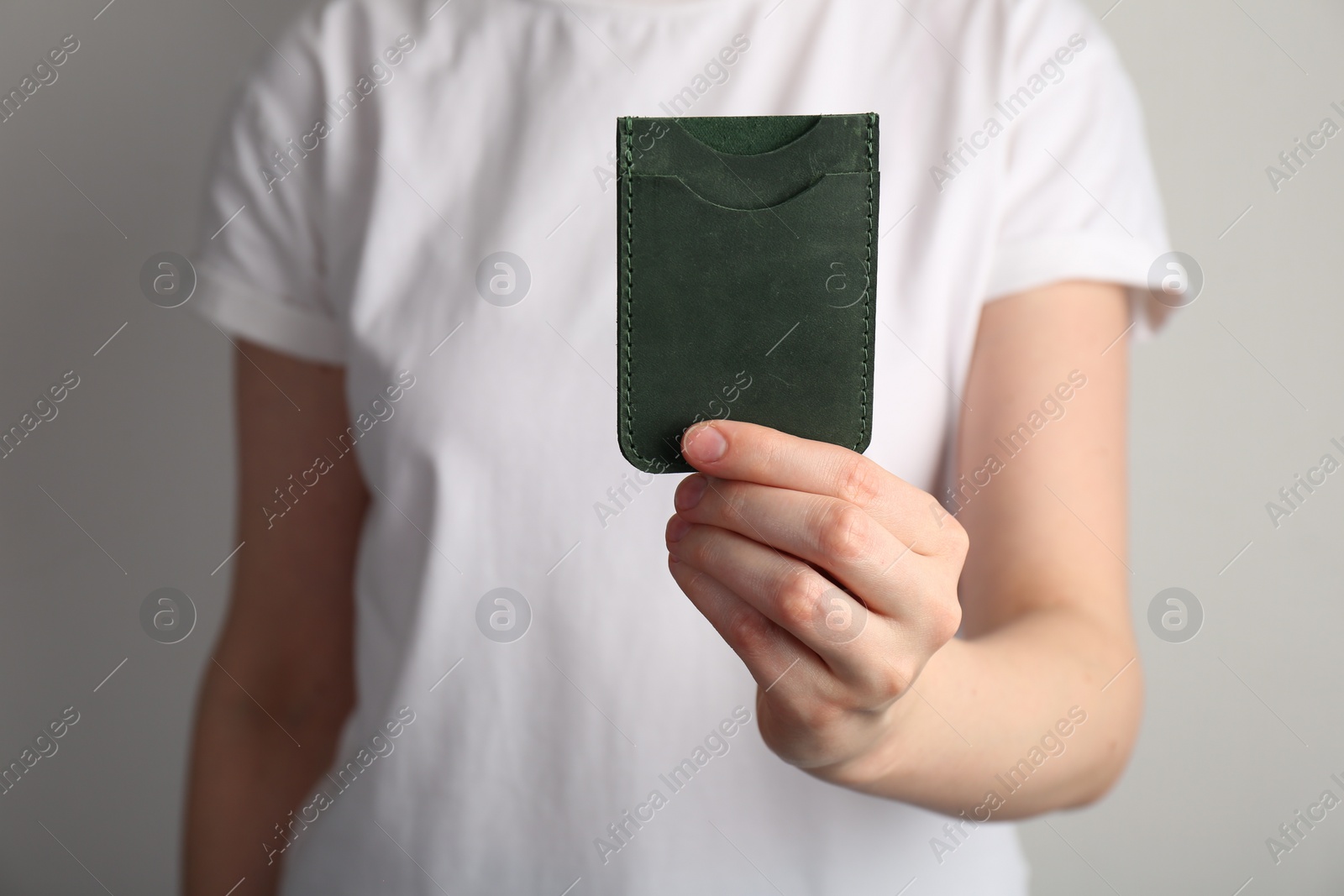 Photo of Woman holding leather business card holder on grey background, closeup