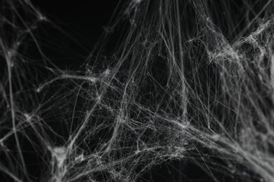 Photo of Creepy white cobweb on black background, closeup