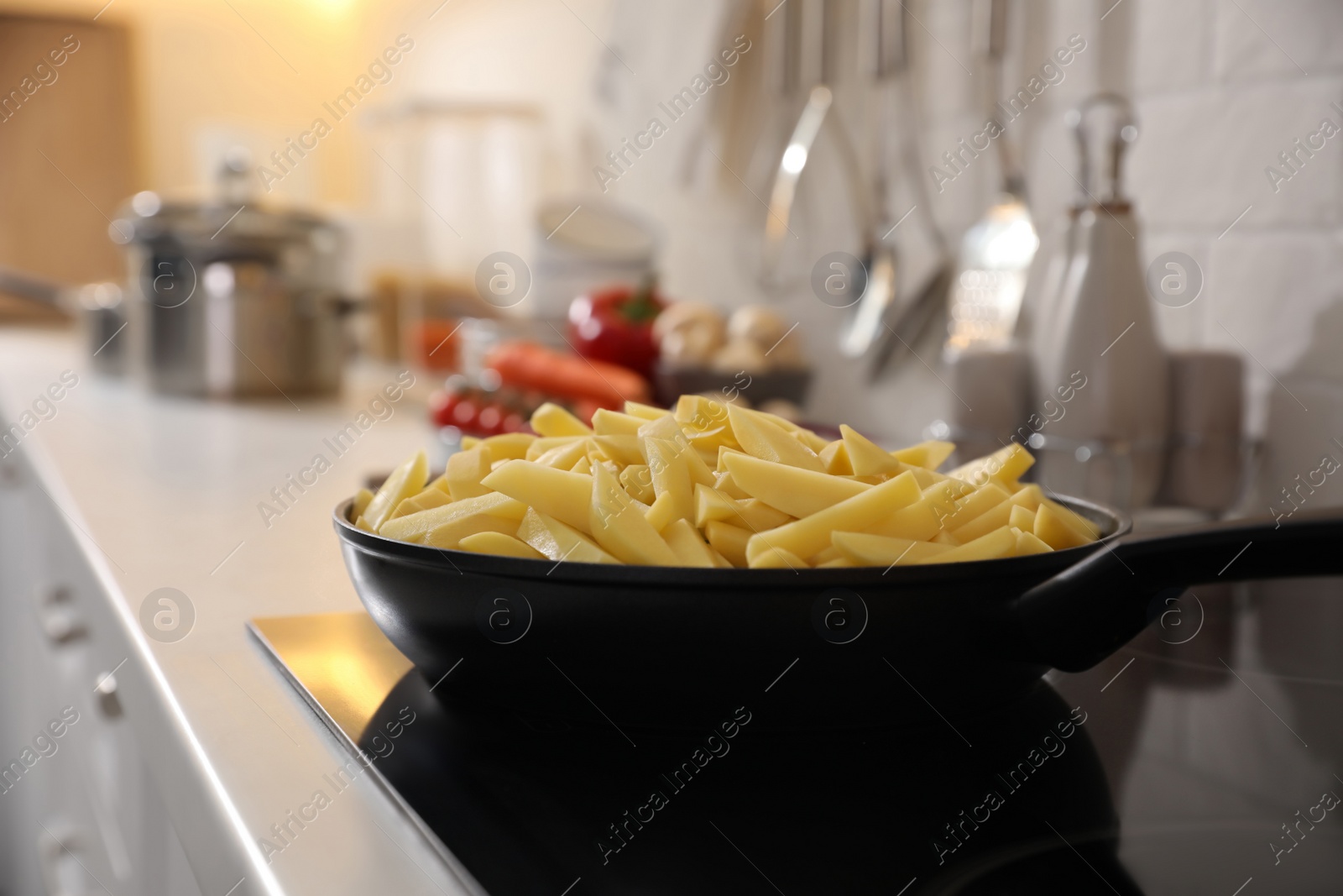 Photo of Frying pan with cut raw potatoes on cooktop
