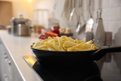 Frying pan with cut raw potatoes on cooktop