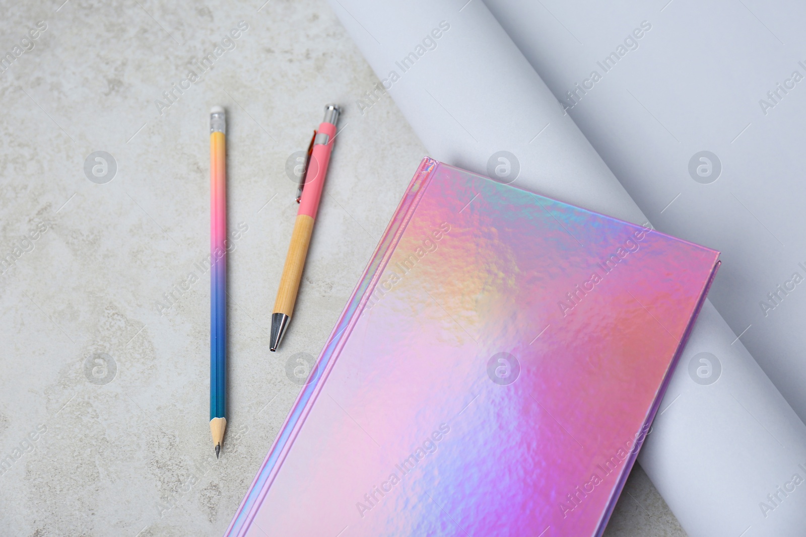 Photo of Beautiful notebook, pencil, pen and rolled paper on table