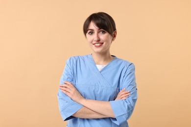 Photo of Portrait of smiling medical assistant with crossed arms on beige background