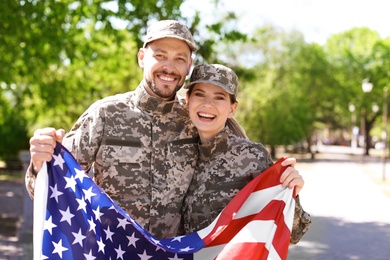 Photo of Military couple with American flag in park