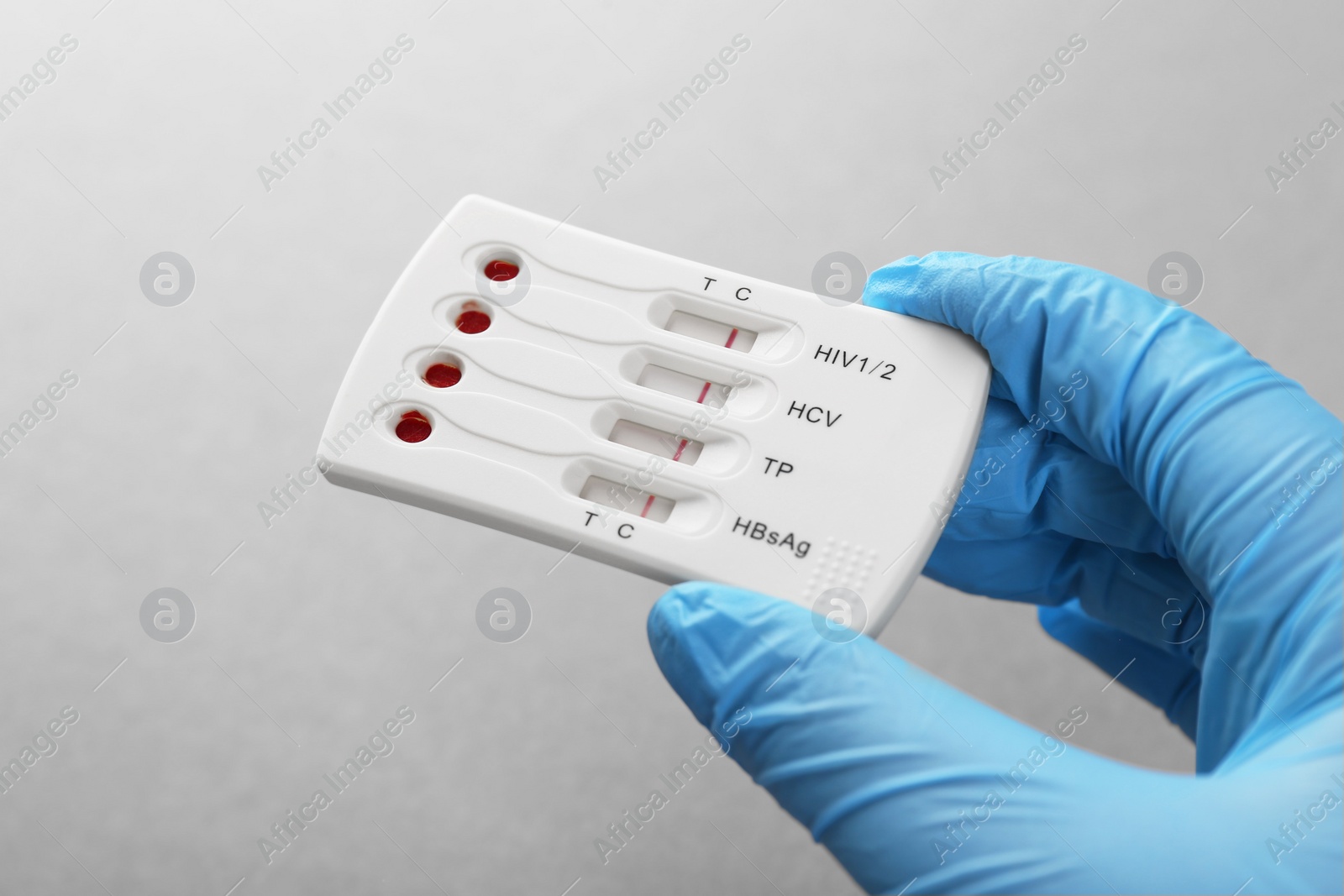 Photo of Doctor holding disposable multi-infection express test on light grey background, closeup