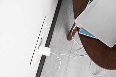 Photo of Electric power outlet sockets with charger on white wall, above view