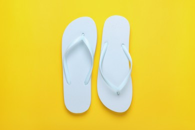 Photo of Stylish white flip flops on yellow background, top view
