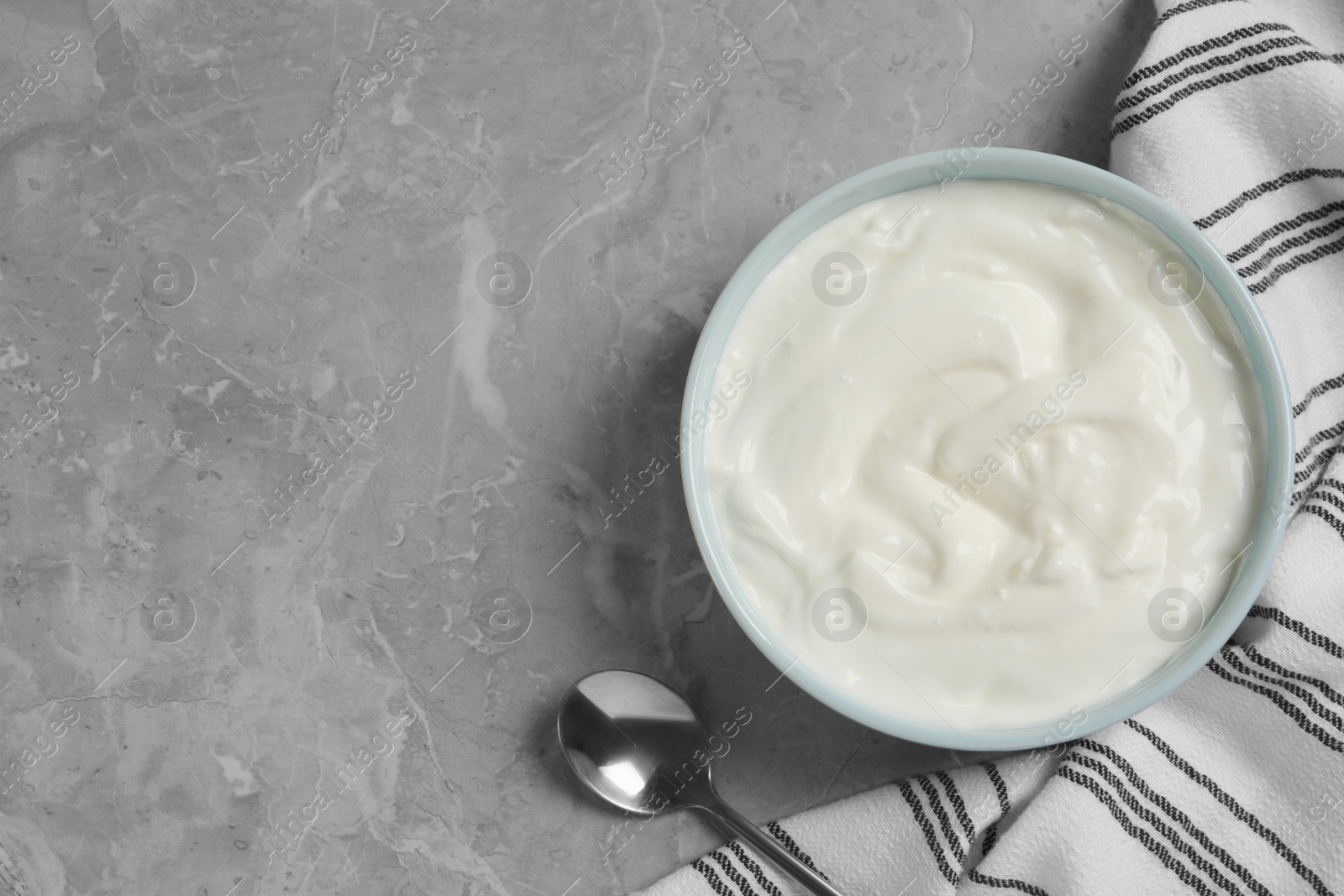 Photo of Bowl of fresh yogurt on grey table, flat lay. Space for text