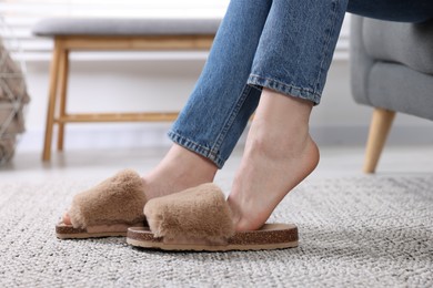 Photo of Woman in brown soft slippers at home, closeup