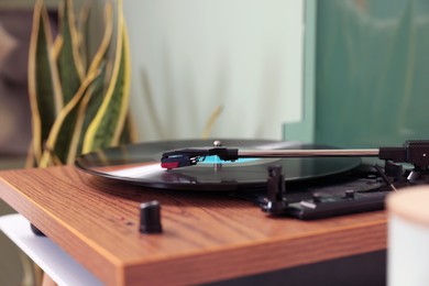 Stylish turntable with vinyl record indoors, closeup