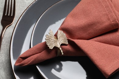 Photo of Fabric napkin and decorative ring for table setting on gray plate, closeup