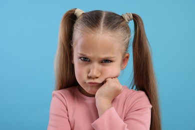 Photo of Portrait of resentful girl on light blue background