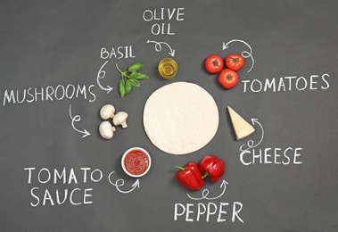 Photo of Pizza crust, ingredients and chalk written product's names on dark background, flat lay
