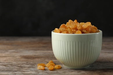 Bowl with raisins on wooden table, space for text. Dried fruit as healthy snack