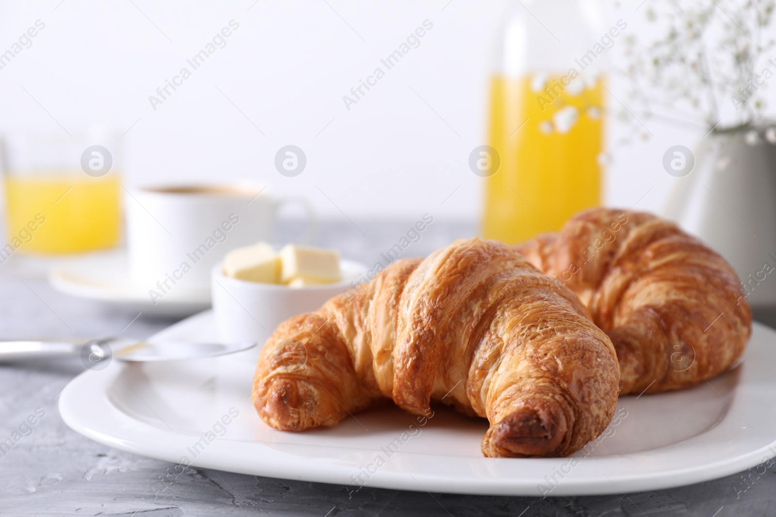 Photo of Tasty breakfast. Fresh croissants and butter on grey table, closeup