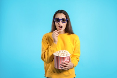 Photo of Emotional woman with 3D glasses and popcorn during cinema show on color background