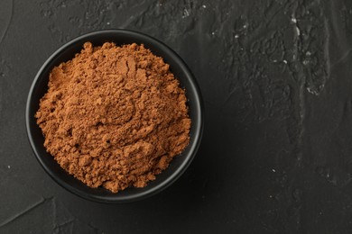 Photo of Aromatic cinnamon powder on black table, top view. Space for text