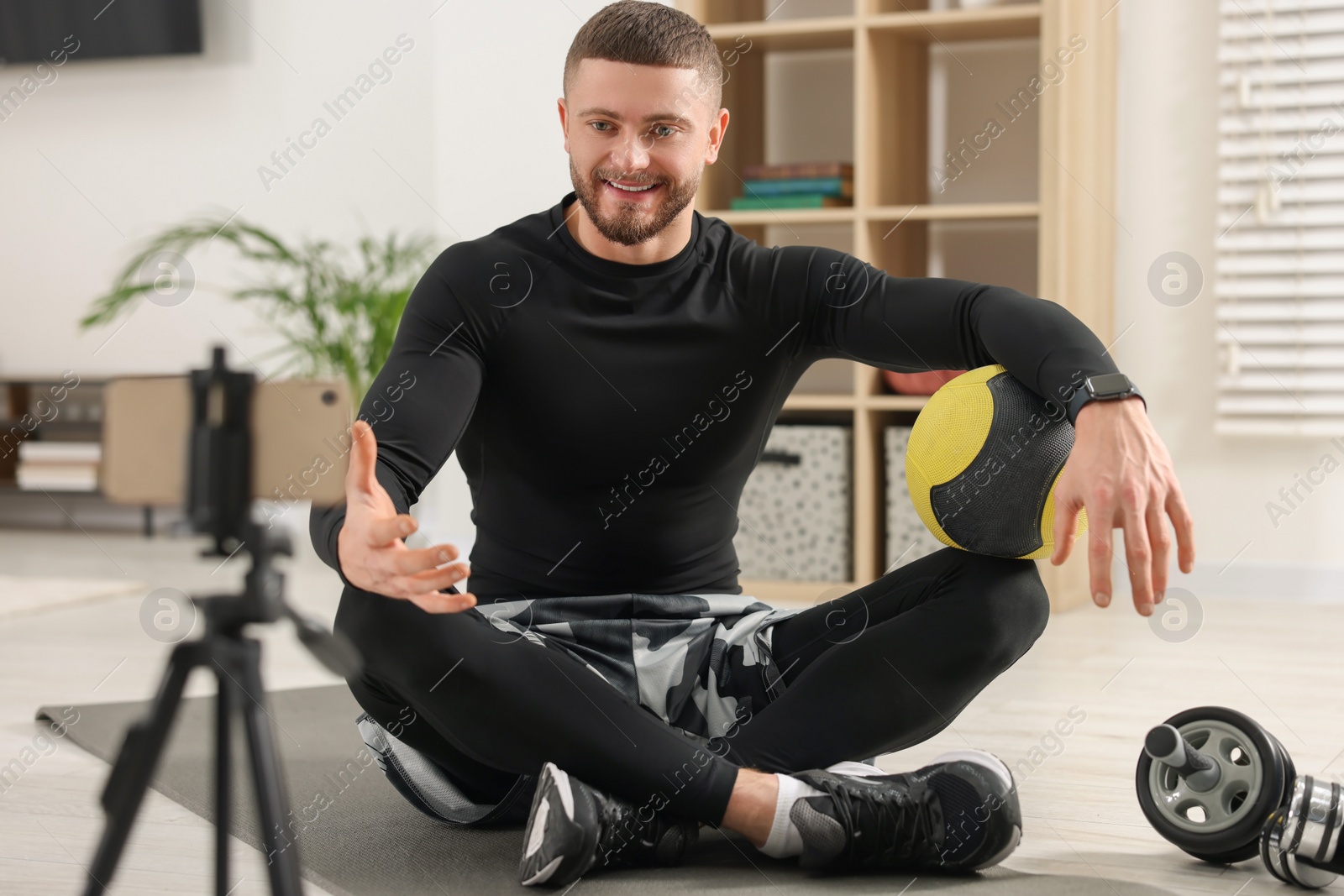 Photo of Trainer with ball streaming online fitness lesson on phone at home