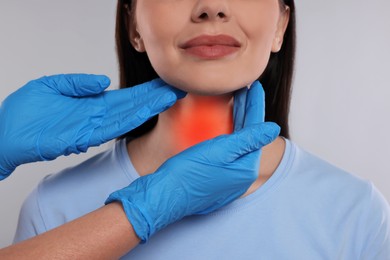 Image of Endocrinologist examining thyroid gland of patient on light grey background, closeup