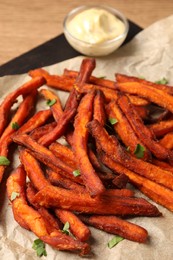Board with delicious sweet potato fries and sauce on wooden table, closeup