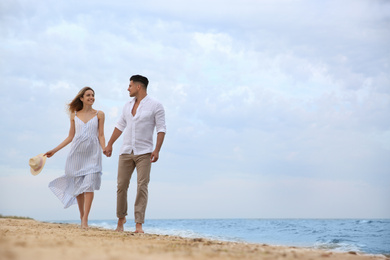 Happy couple having romantic walk on beach. Space for text