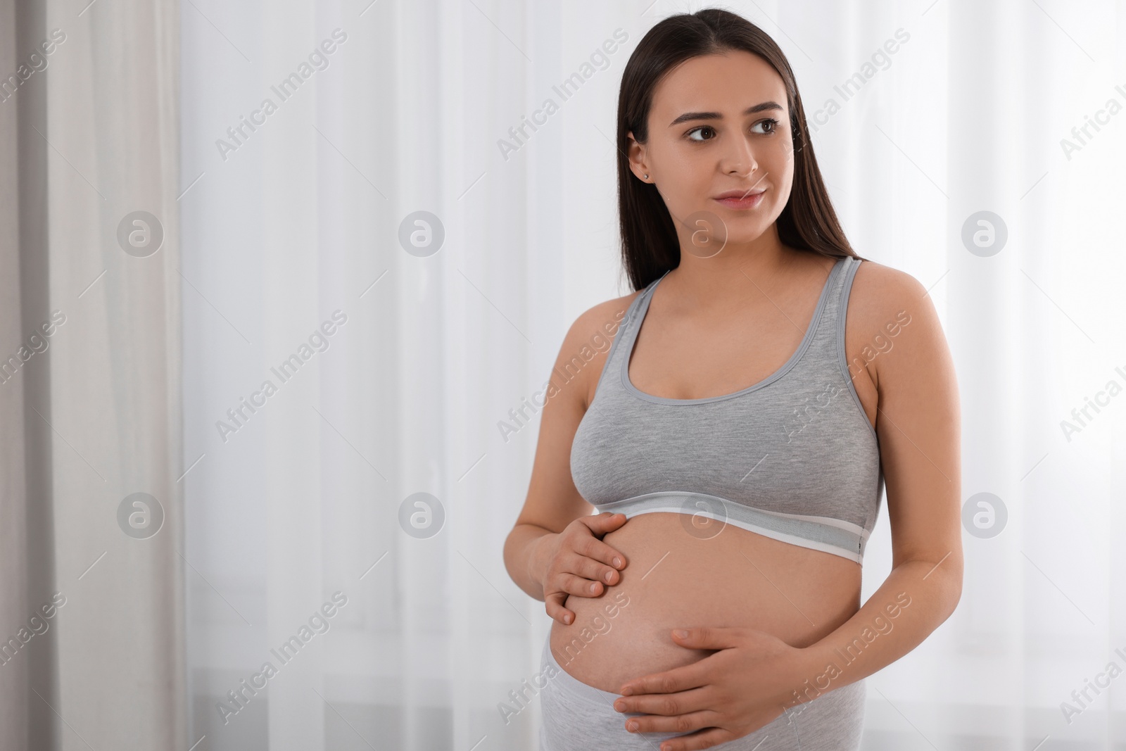 Photo of Beautiful pregnant woman in comfortable maternity underwear indoors, space for text