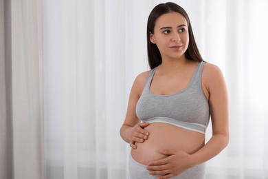 Photo of Beautiful pregnant woman in comfortable maternity underwear indoors, space for text